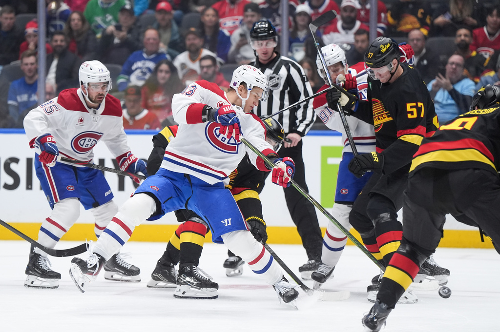Montreal Canadiens' Ivan Demidov, center, shoots on goal as teammate Oliver Kapanen (91) checks Vancouver Canucks' Tyler Myers (57) during the first period of an NHL hockey game in Vancouver, British Columbia, Saturday, Oct. 25, 2025. (Darryl Dyck/The Canadian Press via AP)