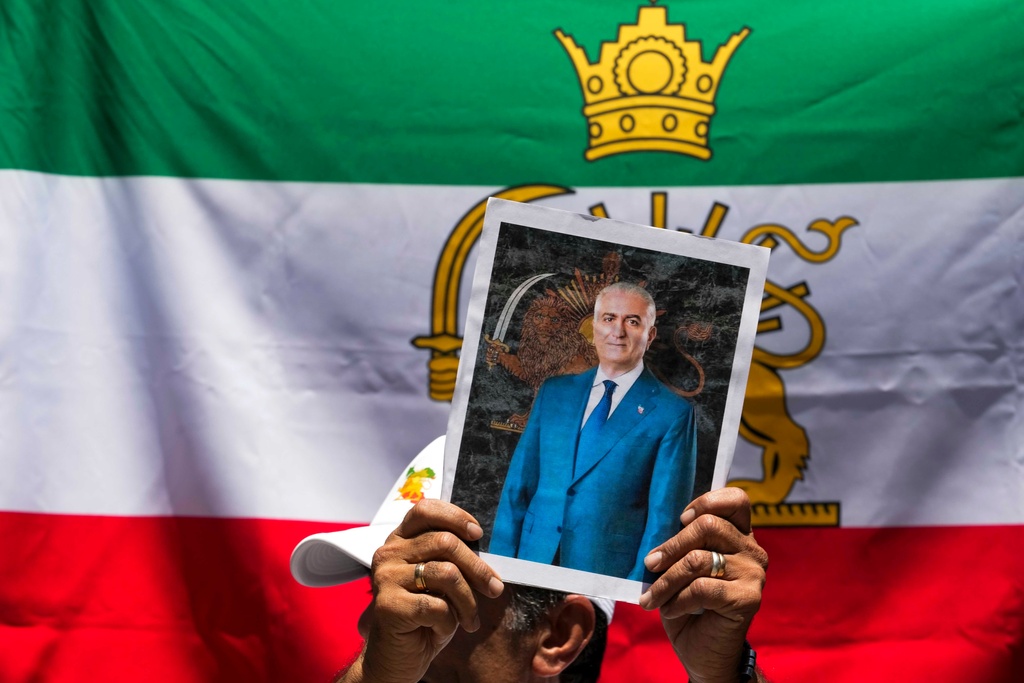 A protester holds a poster of Iran's exiled crown prince Reza Pahlavi during a rally in support of anti-government protests in Iran, outside Iran's embassy in Santiago, Chile, Tuesday, Jan. 13, 2026. (AP Photo/Esteban Felix)