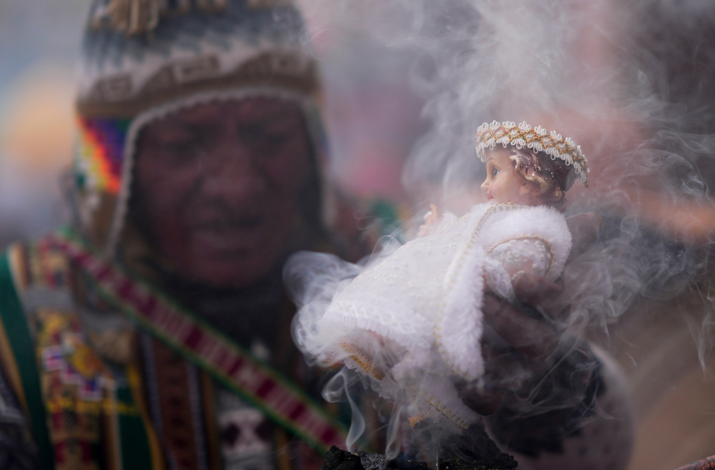 An Aymara Indigenous spiritual guide blesses a statue of baby Jesus with incense after an Epiphany Mass at a Catholic church in La Paz, Bolivia, Jan. 6, 2025. (AP Photo/Juan Karita, File)