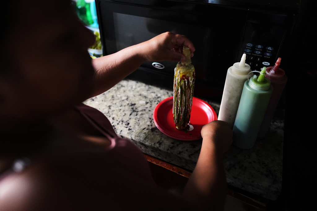 Guatemalan migrant Amavilia, 31, shows how she prepares the corn-on-the-cob she sells, inside her South Florida apartment, Wednesday, Oct. 8, 2025, after her infant son's father, who worked in construction, was detained and deported to Guatemala. (AP Photo/Rebecca Blackwell)