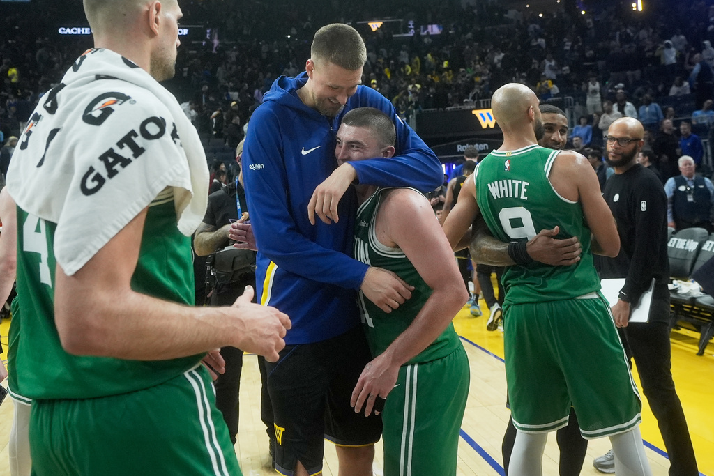 Golden State Warriors center Kristaps Porziņģis, top middle, hugs Boston Celtics guard Payton Pritchard as Celtics guard Derrick White (9) hugs Warriors guard Gary Payton II after an NBA basketball game in San Francisco, Thursday, Feb. 19, 2026. (AP Photo/Jeff Chiu)