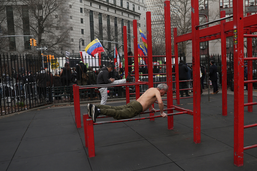 Men work out in Columbus Park as people protest outside Manhattan federal court before a pre-trial hearing in former Venezuela President Nicolas Maduro's drug trafficking case, Thursday, March 26, 2026, in New York. (AP Photo/Heather Khalifa)