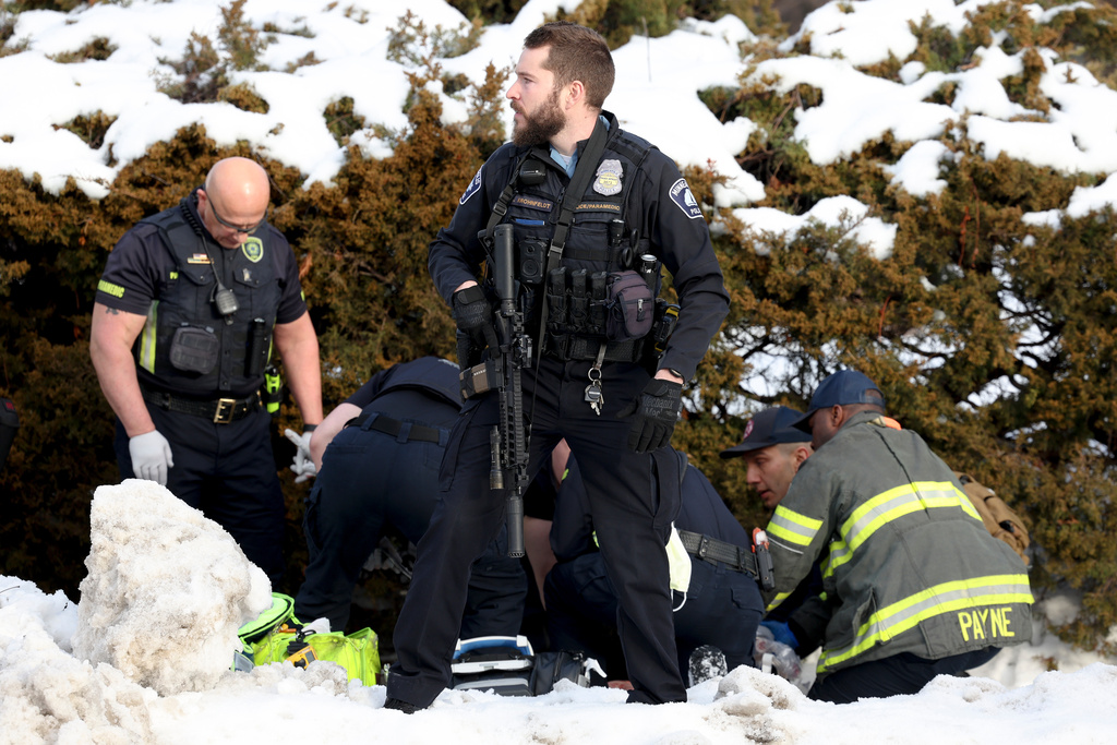 A Minneapolis police officer stands guard while emergency medical technicians administer aid to a person who was shot by a Immigration and Customs Enforcement officer in Minneapolis on Wednesday, Jan. 7, 2026. (Ellen Schmidt/MinnPost via AP)