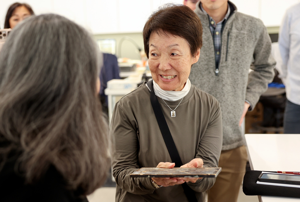Karen Okawa, Japanese Church of Christ member and time capsule committee member, reacts as she holds a heavy lid that was used on the Japanese Church of Christ's 100-year-old time capsule at the University of Utah Marriott Library Preservation Department in Salt Lake City, Monday, Oct. 20, 2025. (Kristin Murphy/The Deseret News via AP)
