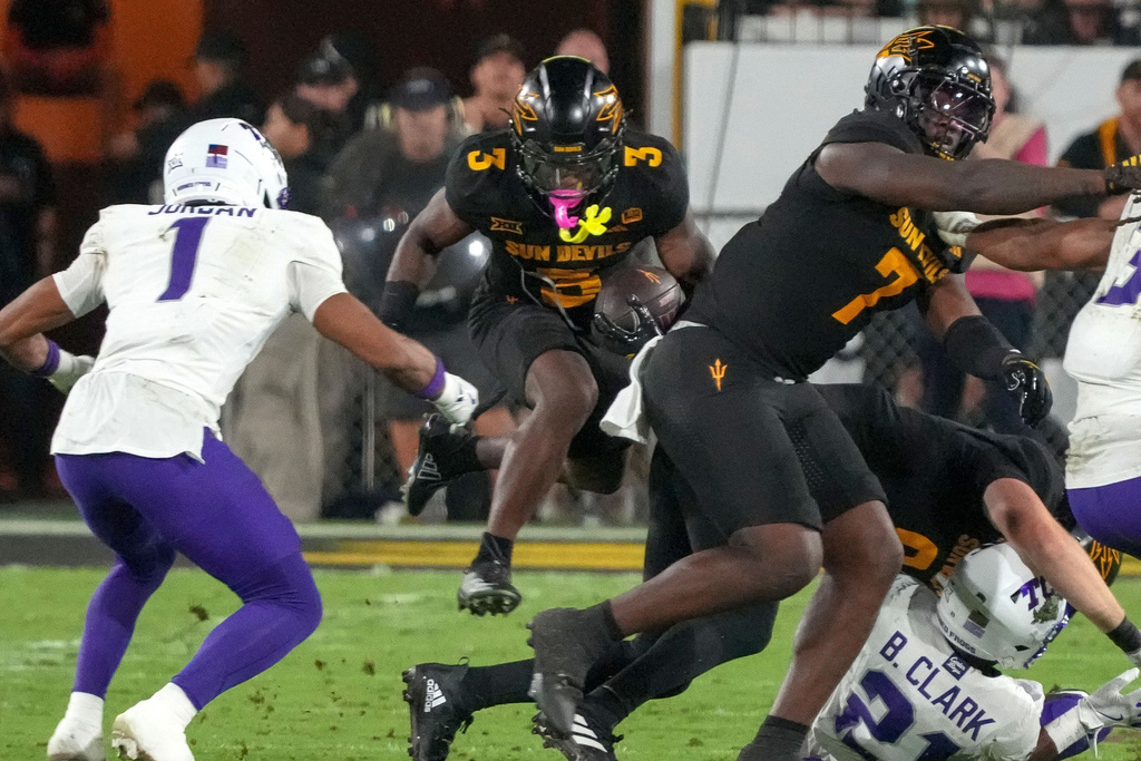 Arizona State Sun Devils running back Raleek Brown (3) finds a hole to jump through against TCU Horned Frogs safety Austin Jordan (1) during the first half of an NCAA college football game Friday, Sept. 26, 2025, in Tempe, Ariz. (AP Photo/Darryl Webb)