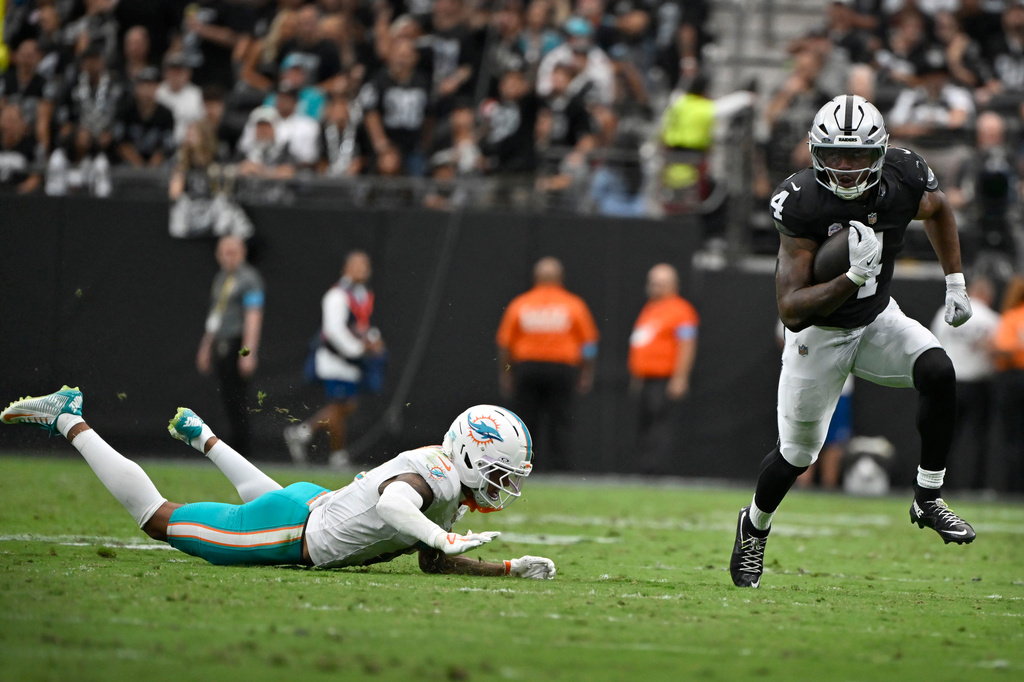 Las Vegas Raiders running back Mike Washington Jr. (4) runs from Miami Dolphins cornerback Juju Brents during the first half of an NFL football game, Sunday, Sept. 13, 2026, in Las Vegas. (AP Photo/David Becker)