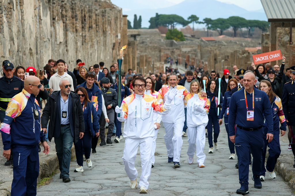 Actor Jackie Chan holds the olympic torch passing through the Archaeological Park in Pompeii, Italy, Monday, Dec. 22, 2025. (Alessandro Garofalo/LaPresse via AP)