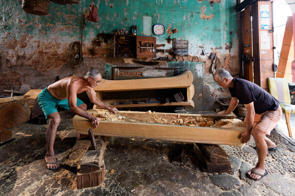 Traditional Chinese coffin maker Goh Khuay Par, left, and his brother Goh Khuay Hou shape one of the wooden sections during the early stages of making a Mei Hua coffin at their workshop in Muar, Malaysia, Wednesday, July 29, 2026. (AP Photo/Vincent Thian)