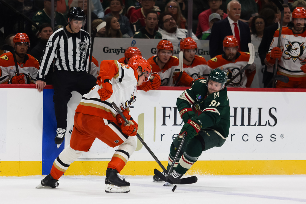 Anaheim Ducks' Jackson LaCombe (2) and Minnesota Wild's Vladimir Tarasenko (91) chase down the puck during the first period of an NHL hockey game Tuesday, April 14, 2026, in St. Paul, Minn. (AP Photo/Lily Dozier)