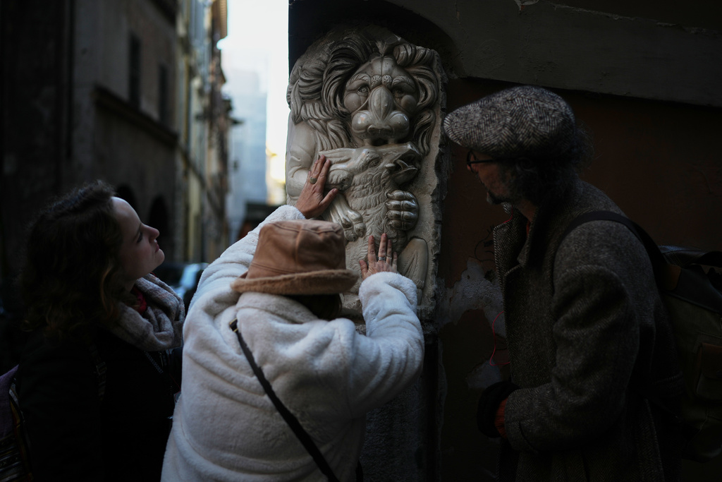 Francesca Inglese, who is blind, touches a marble relief on the corner of a building during an inclusive art tour in downtown Rome, on Nov. 29, 2025. (AP Photo/Alessandra Tarantino)