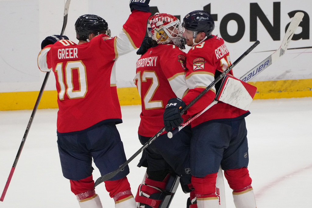 Florida Panthers goaltender Sergei Bobrovsky, center, celebrates with center Sam Reinhart, right, and left wing A.J. Greer (10) after making the winning save during overtime of an NHL hockey game against the Carolina Hurricanes, Friday, Dec. 19, 2025, in Sunrise, Fla. (AP Photo/Jim Rassol)