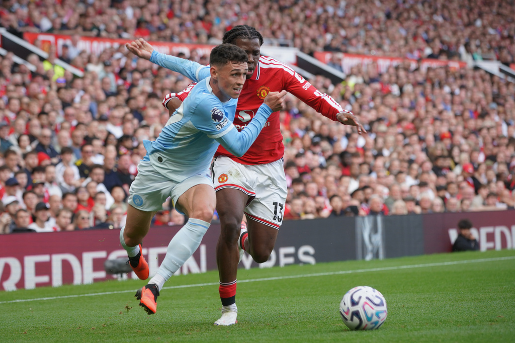 Manchester City's Phil Foden, left, challenges for the ball with Manchester United's Patrick Dorgu during the English Premier League soccer match between Manchester United and Manchester City in Manchester, England, Sunday, Sept. 13, 2026. (AP Photo/Ian Hodgson)