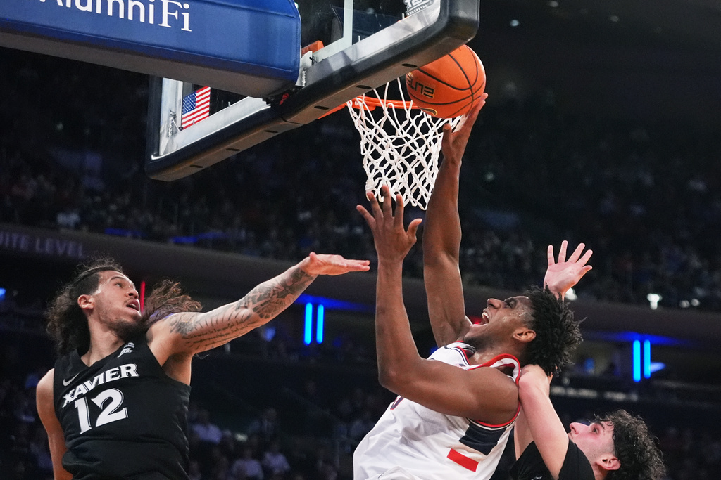 UConn's Tarris Reed Jr., center, shoots over Xavier's Tre Carroll, left, and Jovan Milicevic during first half of an NCAA college basketball game in the quarterfinals of the Big East basketball tournament Thursday, March 12, 2026, in New York. (AP Photo/Frank Franklin II)