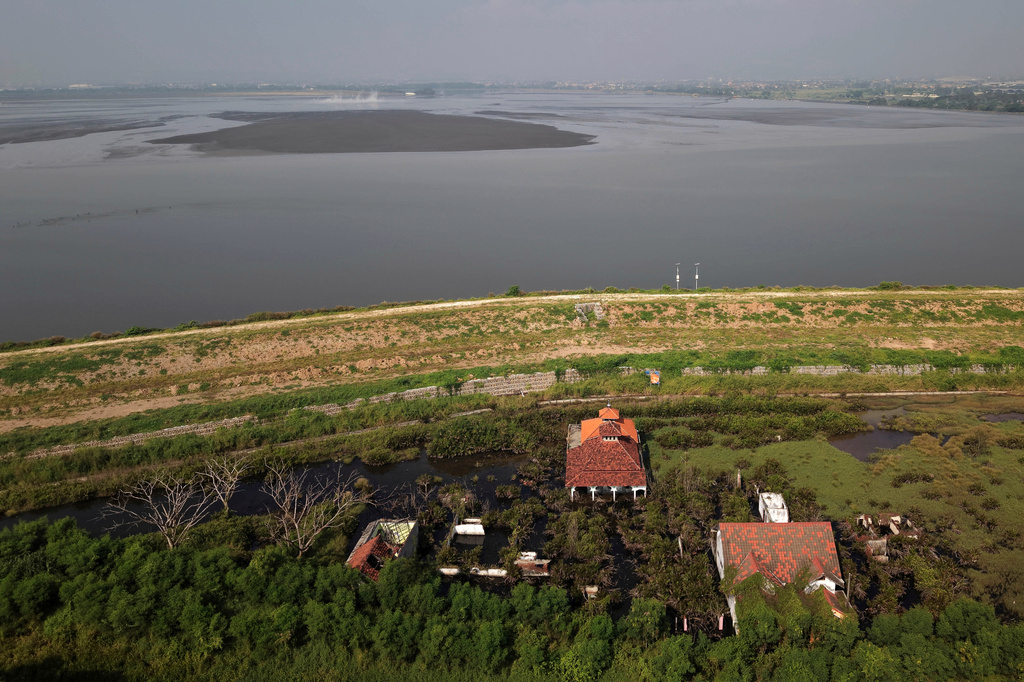 Abandoned houses and mosque are seen near the dyke built to contain hot mud that has been flowing since a gas exploration accident occurred in 2006, in Sidoarjo, East Java, Indonesia, Friday, May 29, 2026. (AP Photo/Trisnadi)