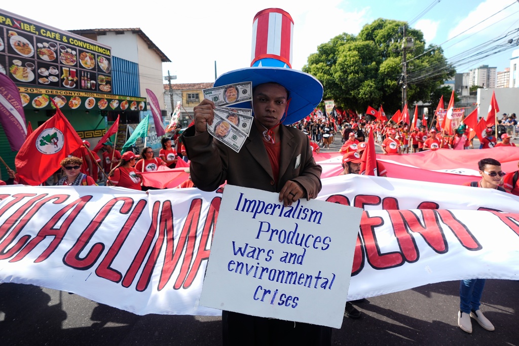 Flavio Pinto participates in a climate protest holding money with President Donald Trump's face on it during the COP30 U.N. Climate Summit, Saturday, Nov. 15, 2025, in Belem, Brazil. (AP Photo/Fernando Llano)