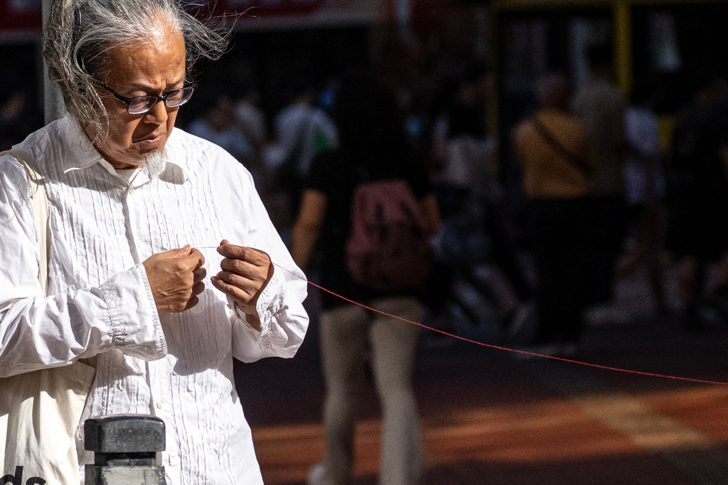 Artist Sanmu Chen displays a red thread as he performs on the street in the Causeway Bay area on the eve of the 37th anniversary of China's Tiananmen Square crackdown in Hong Kong, Wednesday, June 3, 2026. (AP Photo/Chan Long Hei)