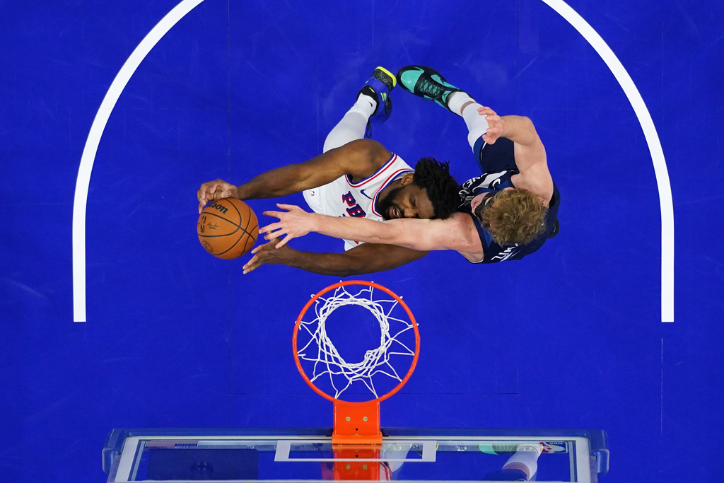 Philadelphia 76ers' Joel Embiid, left, cannot get a shot past Minnesota Timberwolves' Rocco Zikarsky during the first half of an preseason NBA basketball game Friday, Oct. 17, 2025, in Philadelphia. (AP Photo/Matt Slocum)