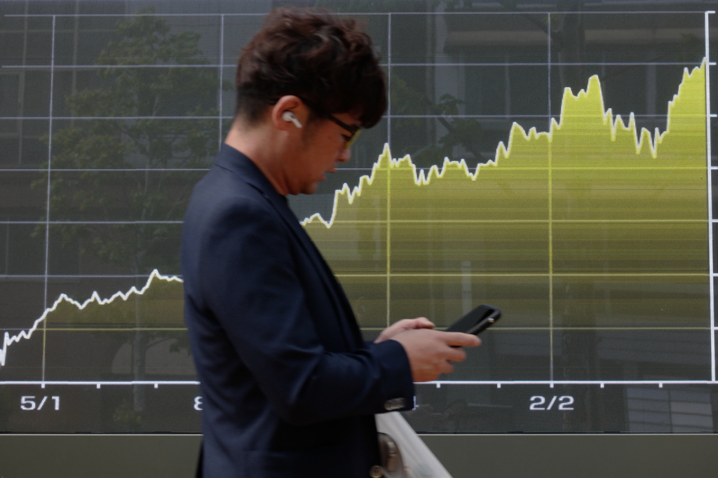 A person walks in front of an electronic stock board chart showing Japan's Nikkei index at a securities firm, Tuesday, April 28, 2026, in Tokyo. (AP Photo/Eugene Hoshiko)