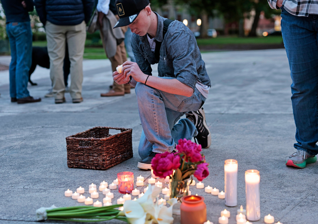 Kaeden Beck, 16, lays down candles during an evening prayer and vigil, in support for the victims and their families impacted by Nippon Dynawave Packaging Co. tank implosion, at R.A. Long Park in Longview, Wash., on Tuesday, May 26, 2026. (Karen Ducey/The Seattle Times via AP)