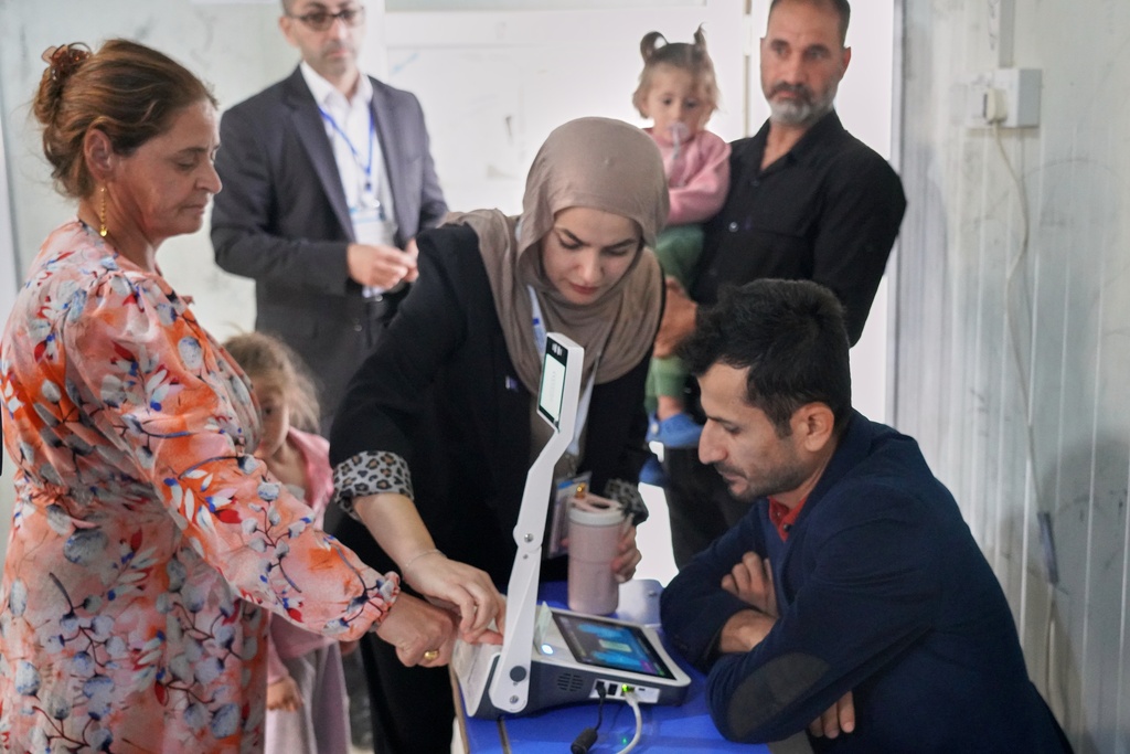 A displaced Yazidi woman has her fingerprint verified before voting ahead of Iraq's parliamentary elections, set for Nov. 11, at a polling station in the Sharia camp near Dohuk, in Iraq's semi-autonomous Kurdish region, Sunday, Nov. 9, 2025. (AP Photo/Rashid Yahya)