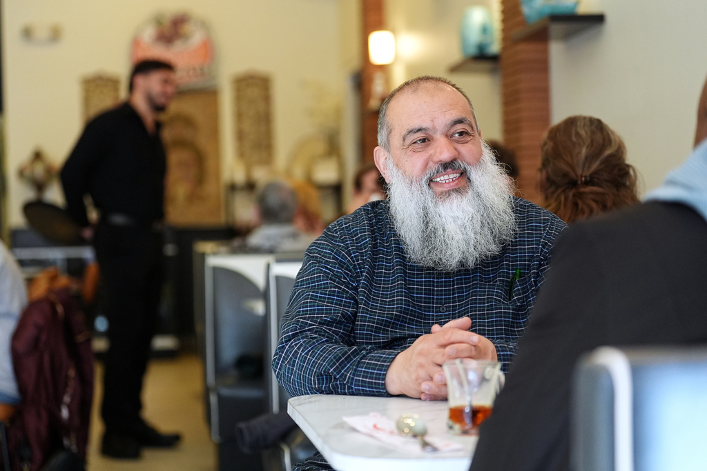 Celal Emanet sits with guest Kenneth Moore at the Jersey Kebab restaurant, Thursday, Jan. 29, 2026, in Collingswood, N.J. (AP Photo/Matt Rourke)