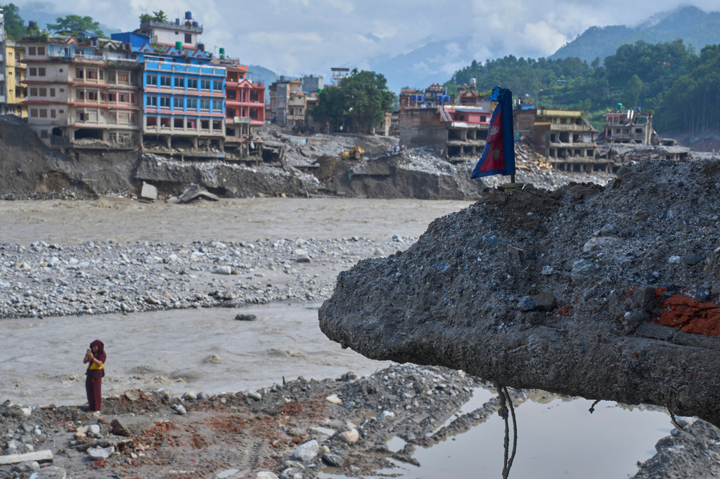 A monk takes photos near a house damaged by flash floods on the bank of Trishuli river, Dhunge, Nuwakot district, Nepal, Monday, Sept. 7, 2026. (AP Photo/Niranjan Shrestha)