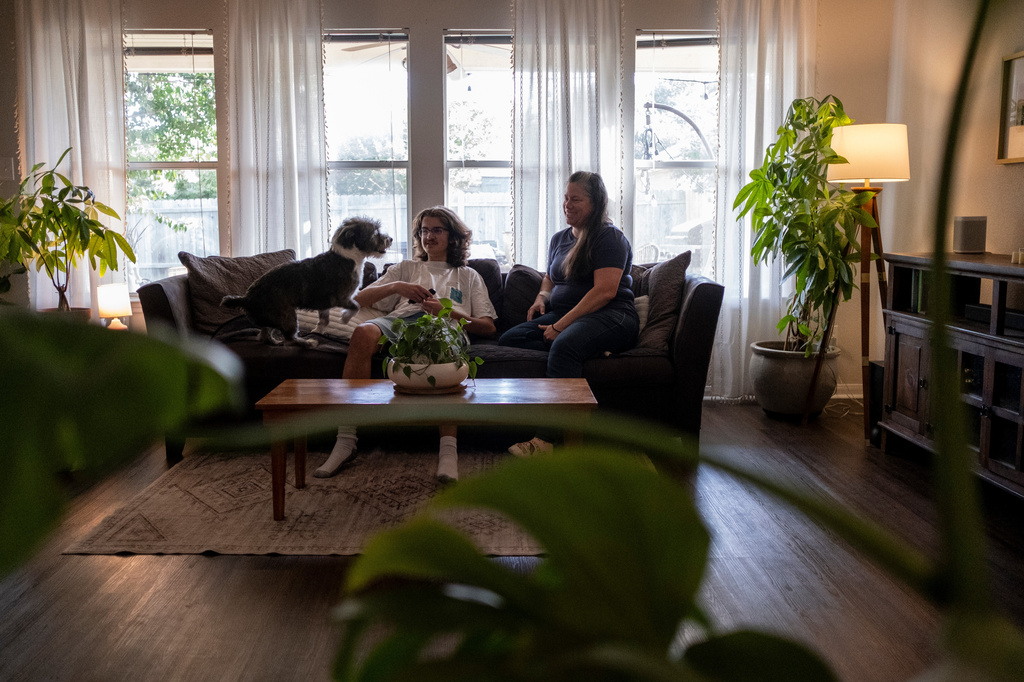 Cash Edgar, 17, sits next to his mother Jamie Corum and dog Oslo at their home on Monday, June 29, 2026, in Pflugerville, Texas. (AP Photo/Joel Angel Juarez)