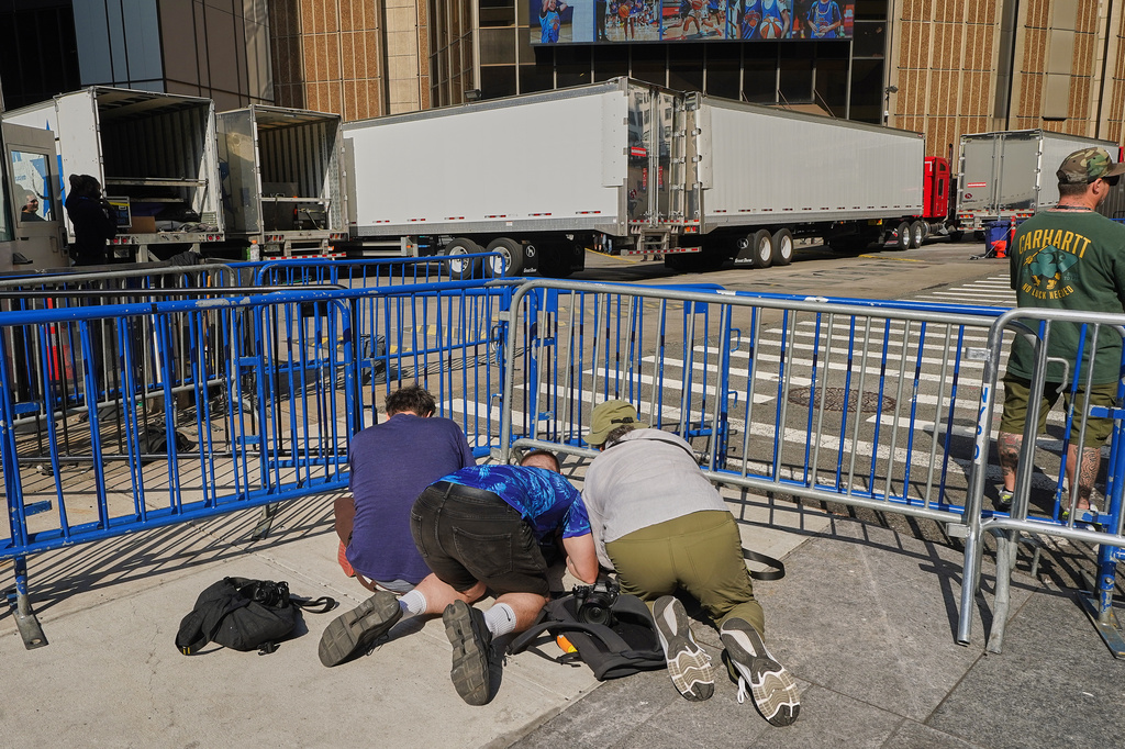 Photographers try to shoot under trucks attempting to block the loading dock at New York's Madison Square Garden, Wednesday, July 1, 2026. (AP Photo/Richard Drew)