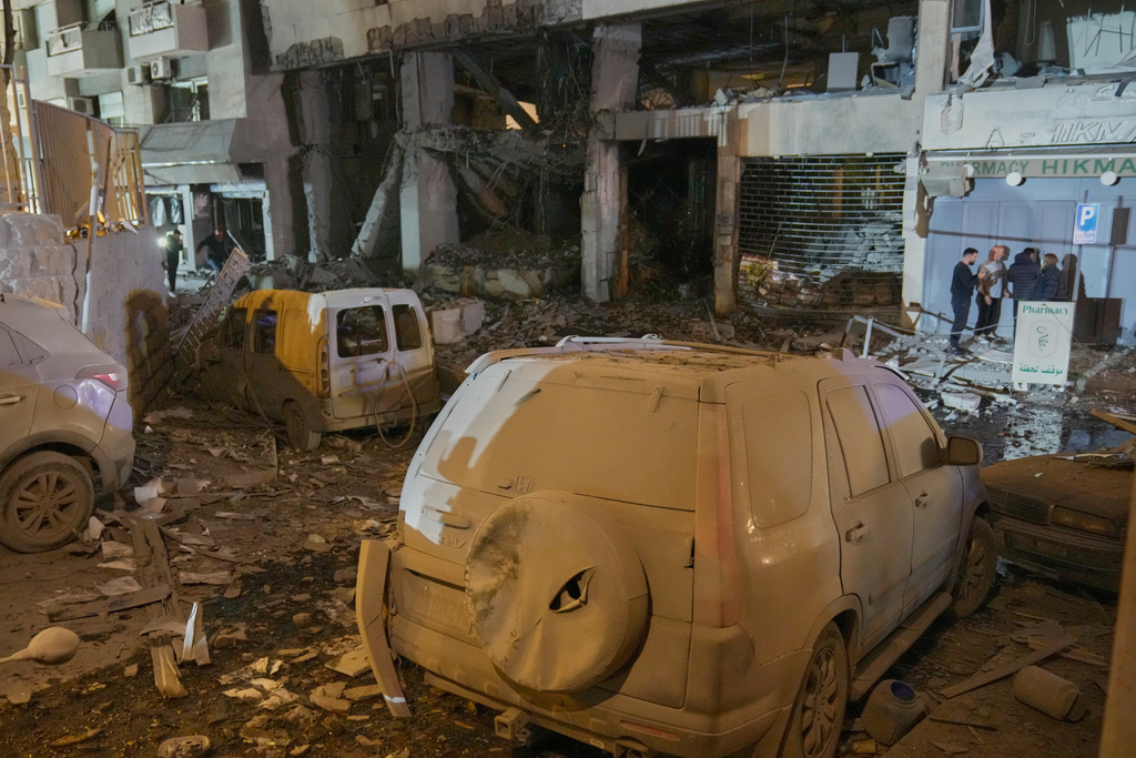 People inspect the site of a destroyed branch of Al-Qard Al-Hassan, a non-bank financial institution run by Hezbollah, which was hit by an Israeli airstrike in central Beirut, Thursday, March 12, 2026. (AP Photo/Hussein Malla)
