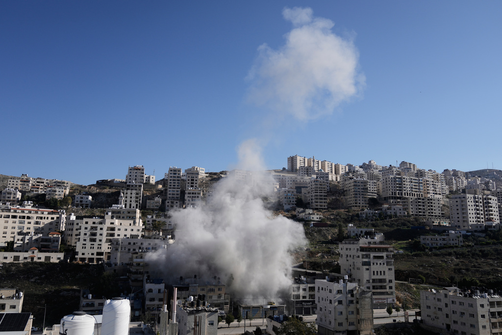 Smoke rises as Israeli forces demolish the home of Abdul Karim Sanoubar, a suspected Palestinian militant who has been accused by Israel of planting bombs on buses in central Israel, in Nablus, West Bank, Tuesday, Dec. 2, 2025. (AP Photo/Majdi Mohammed)