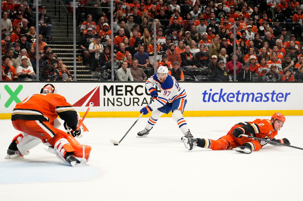 Edmonton Oilers center Connor McDavid, center, tries to get a shot past Anaheim Ducks goaltender Lukas Dostal, left, as defenseman Jackson LaCombe defends during the second period of Game 3 in the first round of the NHL hockey Stanley Cup playoffs series Friday, April 24, 2026, in Anaheim, Calif. (AP Photo/Mark J. Terrill)