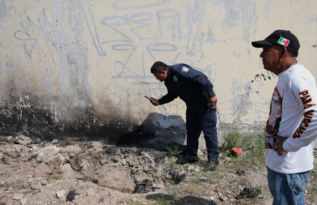 A police officer takes a photo at the site where a relative of a missing person, part of a group called the Guerreros Buscadores, found skeletal remains buried in Tlajomulco de Zuniga, on the outskirts of Guadalajara, Mexico, Tuesday, March 24, 2026. (AP Photo/Eduardo Verdugo)