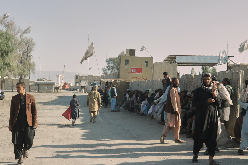 People wait near the closed gate at the Spin Boldak border crossing with Pakistan, after the border was shut for nearly two weeks following clashes between Afghan and Pakistani forces, in Kandahar province, Afghanistan, Thursday, Oct. 23, 2025. (AP Photo/Sibghatullah)