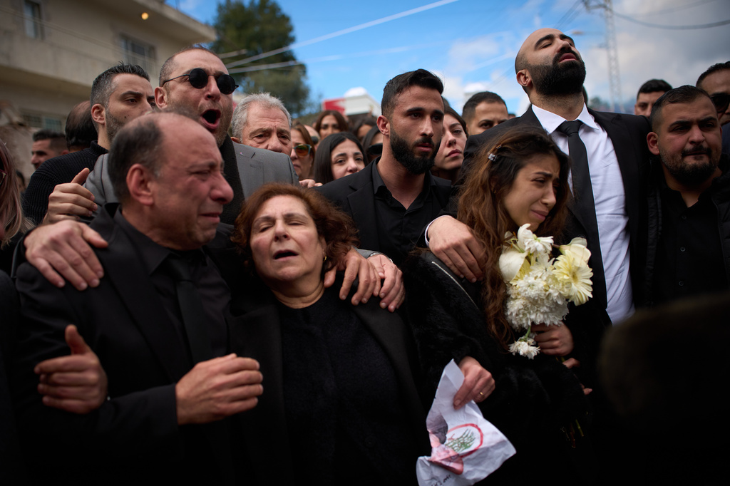 Gyal, right, daughter of Pierre Mouawad, an official with the anti-Hezbollah Lebanese Forces party, and his wife, walks as men carry the bodies of her parents during their funeral in Yahshush, Lebanon, Tuesday, April 7, 2026. (AP Photo/Emilio Morenatti)