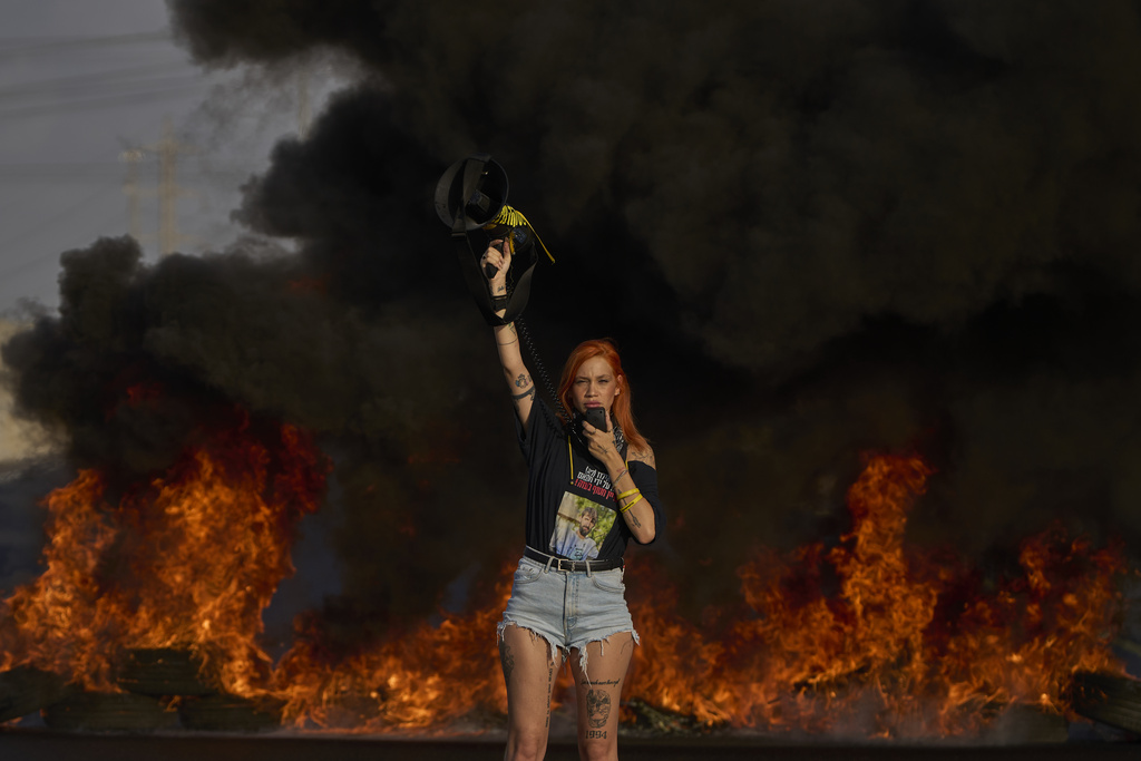 An activist blocks a highway during a protest demanding the immediate release of hostages held by Hamas and calling for the Israeli government to reverse its decision to take over Gaza City and other areas in the Gaza Strip, near the city of Lod, Israel, Tuesday, Aug. 26, 2025. (AP Photo/Ohad Zwigenberg)