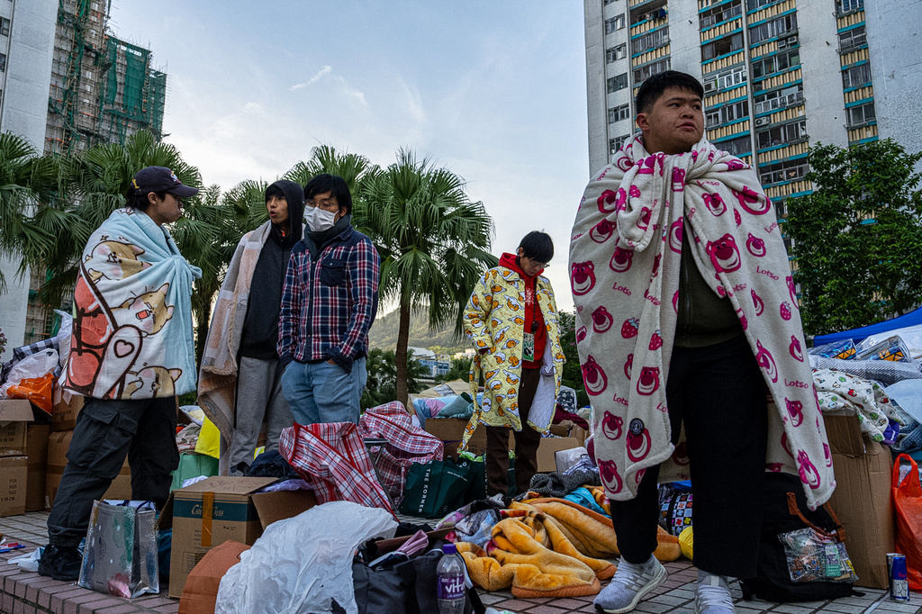 FILE - People stand amid donated supplies following the fire that started Wednesday at Wang Fuk Court, a residential estate in the Tai Po district of Hong Kong's New Territories, Friday, Nov. 28 2025. (AP Photo/Chan Long Hei, File)