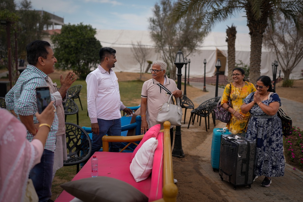 Stranded Indian travelers show their gratitude to Dhiraj Jain, an Indian businessman second from left in a white shirt, at his farmhouse, now converted into a shelter in Ajman, near Dubai, United Arab Emirates, Saturday, March 7, 2026. (AP Photo/Altaf Qadri)