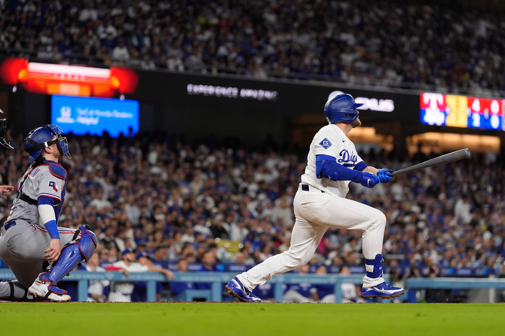 Los Angeles Dodgers' Max Muncy, right, hits a solo home run as Texas Rangers catcher Danny Jansen watches during the fourth inning of a baseball game Friday, April 10, 2026, in Los Angeles. (AP Photo/Mark J. Terrill)