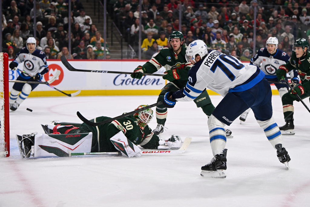 Winnipeg Jets left wing Tanner Pearson (70) hits the puck over Minnesota Wild goaltender Jesper Wallstedt to score a goal during the first period of an NHL hockey game, Thursday, Jan. 15, 2025, in St. Paul, Minn. (AP Photo/Craig Lassig)