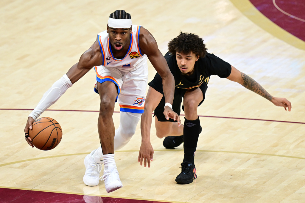 Oklahoma City Thunder guard Shai Gilgeous-Alexander, left, dribbles ahead of Cleveland Cavaliers guard Craig Porter Jr., right, in the second half of an NBA basketball game, Monday, Jan. 19, 2026, in Cleveland. (AP Photo/David Dermer)