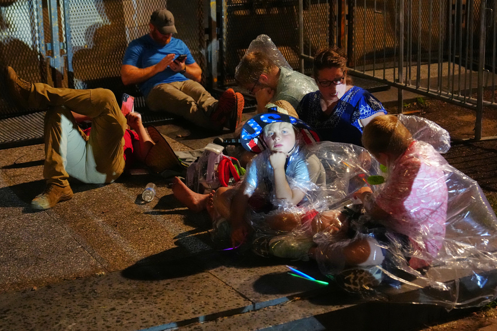 People sit after they were evacuated from the National Mall ahead of severe weather at an Independence Day event and fireworks honoring the nation's 250th anniversary, Saturday, July 4, 2026, in Washington. (AP Photo/Julia Demaree Nikhinson)