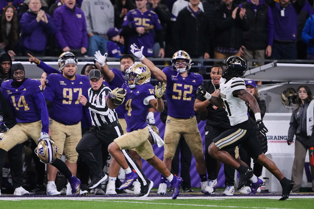 Washington running back Jordan Washington (4) escapes Purdue defensive back Tahj Ra-El (21) to run for a touchdown during the first half of an NCAA college football game, Saturday, Nov. 15, 2025, in Seattle. (AP Photo/Lindsey Wasson)