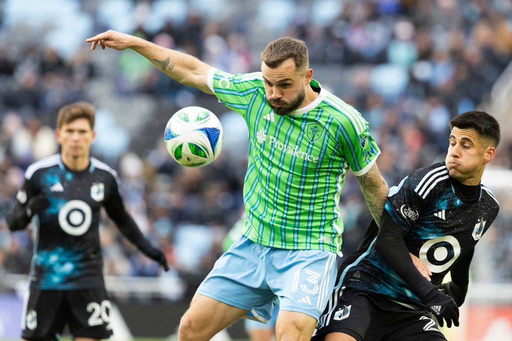 Seattle Sounders forward Jordan Morris (13) and Minnesota United midfielder Joaquín Pereyra, right, collide while competing for the ball during the first half of Game 3 in the first round of MLS soccer's Western Conference playoffs in St. Paul, Minn., Saturday, Nov. 8, 2025. (AP Photo/Ellen Schmidt)