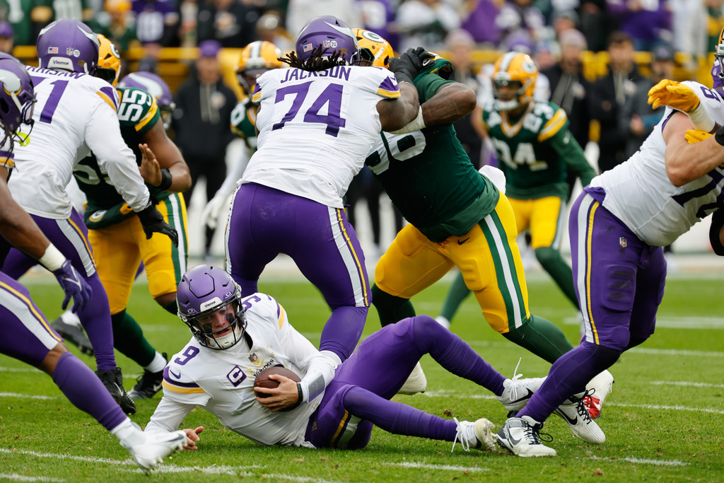 Minnesota Vikings quarterback J.J. McCarthy (9) recovers a fumble during the first half of an NFL football game against the Green Bay Packers Sunday, Nov. 23, 2025, in Green Bay, Wis. (AP Photo/Mike Roemer)