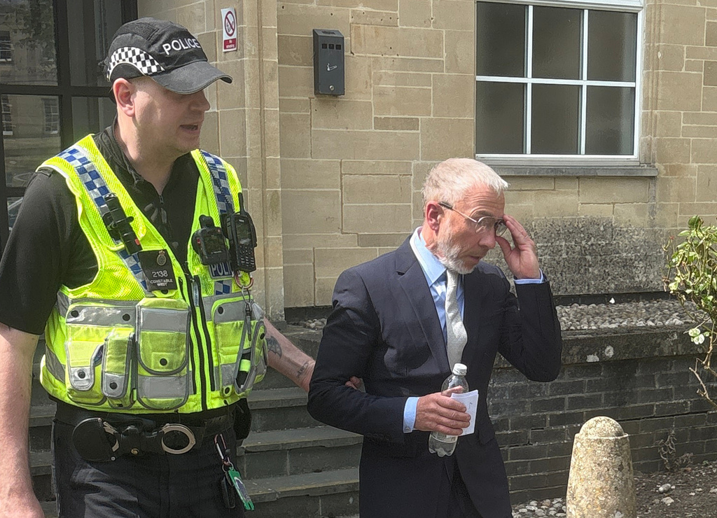 Co-founder of clothing firm Superdry James Holder, is escorted by a police officer as he leaves Cirencester Magistrates' Court, England, Friday, May 1 , 2026. (Rod Minchin/PA via AP)