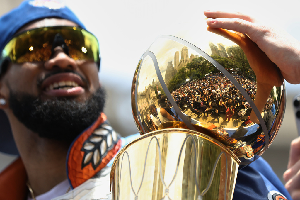 Fans are reflected in a trophy held by New York Knicks center Karl-Anthony Towns during the New York Knicks' NBA championship parade Thursday, June 18, 2026, in New York. (AP Photo/Heather Khalifa)