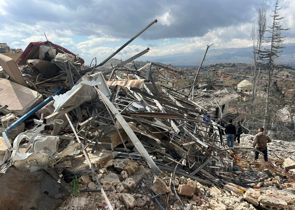 People check the damage left by Israeli airstrikes late Friday, in the village of Nabi Chit, eastern Lebanon, Saturday, March 7, 2026, where Israeli forces landed overnight and dug a grave in a cemetery searching for Israeli co-pilot Ron Arad who was captured and then went missing after his fighter jet crashed over south Lebanon in 1986. (AP Photo/Ali Salem)