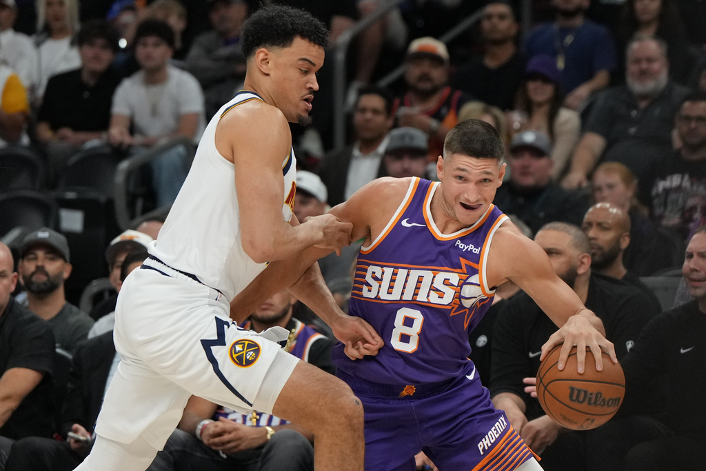 Phoenix Suns guard Grayson Allen (8) drives on Denver Nuggets forward Spencer Jones during the first half of an NBA basketball game, Tuesday, March 24, 2026, in Phoenix. (AP Photo/Rick Scuteri)