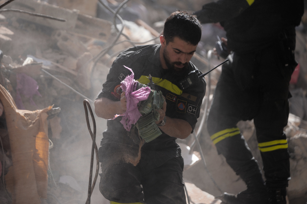 A rescue worker holds money recovered from the rubble of a destroyed building that was hit a day ahead in an Israeli airstrike in central Beirut, Lebanon, Thursday, April 9, 2026. (AP Photo/Hussein Malla)