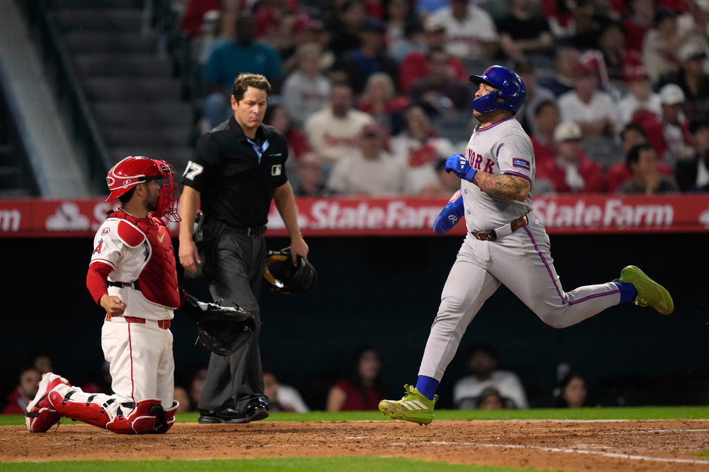 New York Mets catcher Francisco Alvarez, right, scores on a two RBI single by Marcus Semien as Los Angeles Angels catcher Travis D'Arnaud kneels at the plate during the sixth inning of a baseball game Friday, May 1, 2026, in Anaheim, Calif. (AP Photo/Mark J. Terrill)